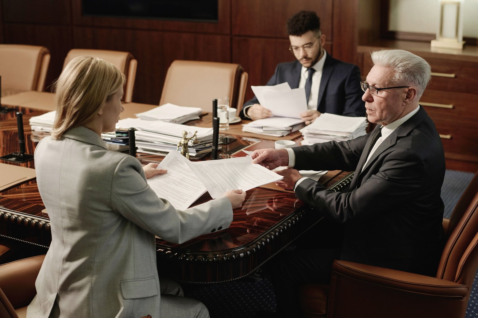 Biracial Group of Attorneys Working with Documents Sitting at Office Table